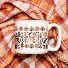 an orange and white plaid blanket with a coffee cup on it, decorated with deers