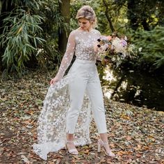 a woman standing in leaves holding a bouquet