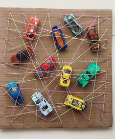 several toy cars are placed on a piece of cardboard with string wrapped around them and pinned together