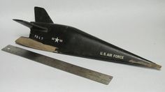 an old model airplane is next to a ruler on a white surface with the words us air force written on it