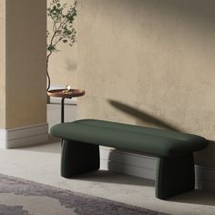 a green bench sitting in front of a wall next to a table with a potted plant on it