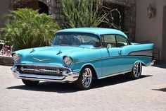 an old blue car parked in front of a building