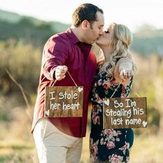 a man and woman kissing in front of a sign that says i stole her heart so i'm stealing his last name