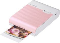 a pink and white printer with donuts on it's side next to an open photo album