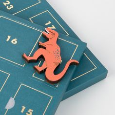 a brooch that is sitting on top of some blue cards with numbers and a lizard