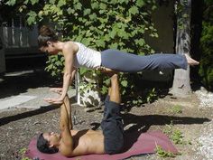 a man and woman doing yoga outside in front of a tree with their hands on the ground