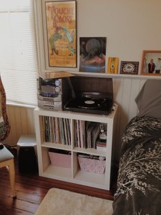 a bedroom with a bed, bookshelf and record player on the side table