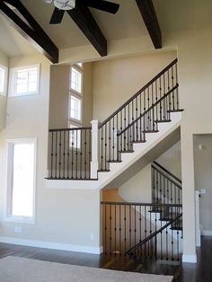 a living room filled with furniture and a stair case next to a window under a ceiling fan