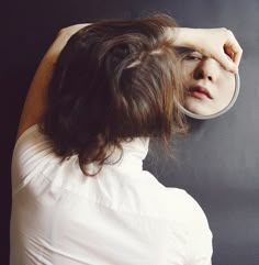 a woman looking at herself in the mirror with her hand on her head and one eye closed