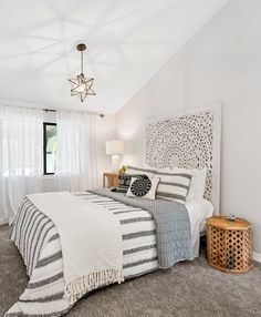 a bedroom with white walls and carpeted flooring has a large bed in the corner