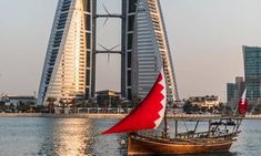 a sailboat in front of a tall building on the water