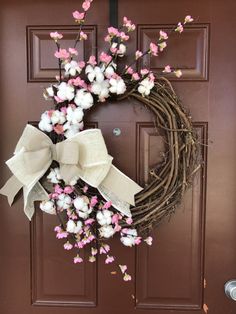 a wreath with pink and white flowers is hanging on the front door