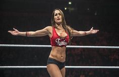 a woman standing on top of a wrestling ring holding her arms out in the air