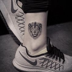 a lion tattoo on the ankle is shown in this black and white photo, with an upper