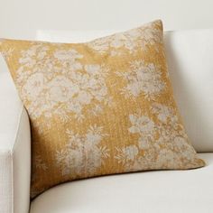 a white couch with a yellow floral pillow on it