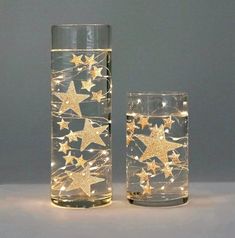 two clear glass vases with gold stars on them and one is filled with water