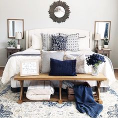 a bed with blue and white pillows on it in a bedroom next to a mirror