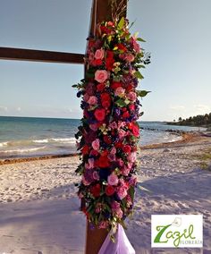 a cross decorated with flowers on the beach