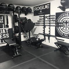 a black and white photo of a home gym with squat racks, weight machines, and wall signs