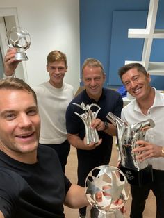 four men are holding up trophies and posing for a photo in front of the camera