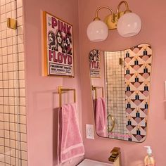 a bathroom with pink walls, gold fixtures and towels hanging on the rack above the sink