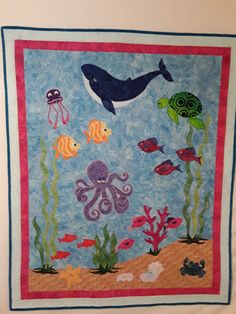 a quilted wall hanging with sea animals and fish