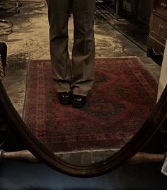 a person standing in front of a mirror on top of a rug with their legs crossed