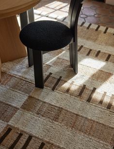 a black chair sitting on top of a rug next to a wooden dining room table