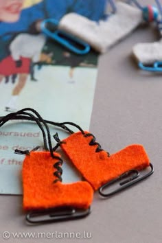 two orange pieces of felt sitting on top of a table next to some paper clips