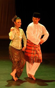 a man and woman dressed in traditional thai garb standing on stage with their arms around each other