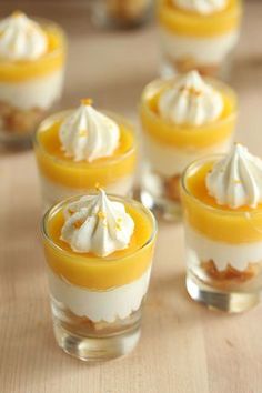 small desserts with whipped cream and orange sauce in glass cups on wooden table top