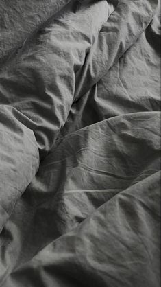 a black and white photo of an unmade bed with the sheets pulled back down