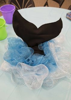 a black and blue hat sitting on top of a table next to some cups with saucers