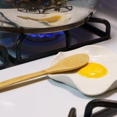 an egg frying pan with two eggs in it and a spatula on the stove