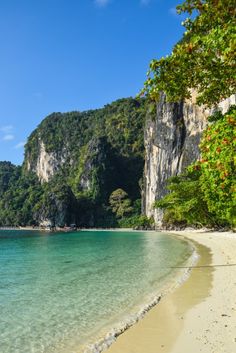 the beach is clear and blue with green trees on both sides in front of it