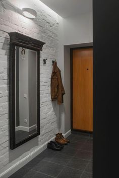 a coat hanging on the wall next to a mirror in a room with white brick walls