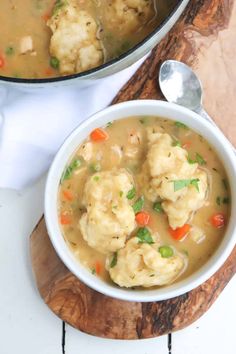 two bowls filled with dumplings and vegetables next to a wooden cutting board