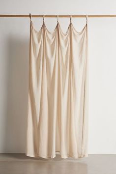 an open curtain hanging on a wooden rod in front of a white wall and floor