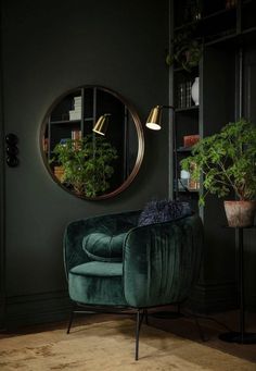 a green velvet chair in front of a round mirror and potted plant on the floor