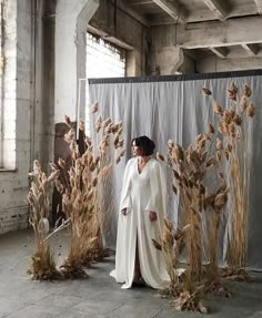 a woman standing in front of some dried plants