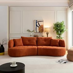 a living room with an orange couch and coffee table in the corner, next to a large window