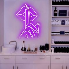 a purple neon sign on the side of a wall next to a sink and cabinets