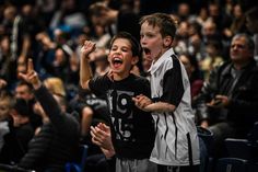 two young boys are cheering in front of an audience