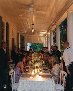 a group of people sitting around a long table with candles on it in front of them