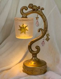 a lamp that is sitting on top of a white cloth covered tablecloth with a gold colored base