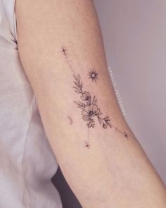 a woman's arm with flowers and stars tattoo on the back of her left arm