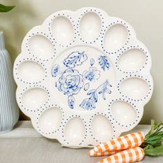 a white plate sitting on top of a table next to a vase and carrots