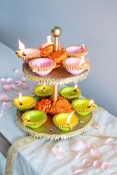 two tiered trays with cupcakes and candles on them sitting on a table