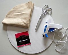 a pair of scissors sitting on top of a white plate next to a bag and some string