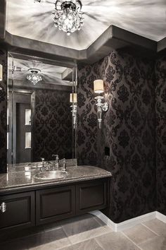 an elegant bathroom with black and white wallpaper, chandelier and marble countertop